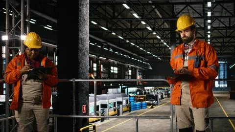 Engineer on laptop, reviewing mechanical systems, massive industry hall Stock Photos