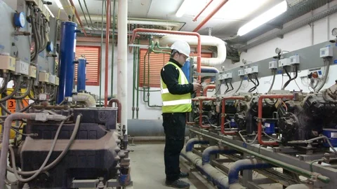 Engineer looking at the high pressure air compressor and writing. Видео 103032456