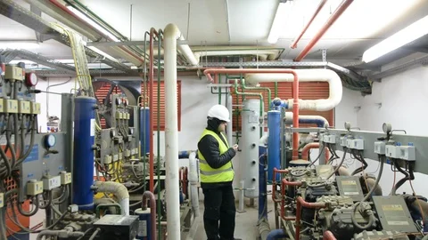 Engineer looking at the high pressure air compressor and writing.	 Vidéo 103868293