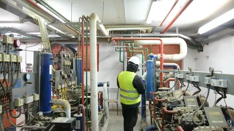 Engineer looking at the high pressure air compressor and writing.	 Video stock 103868479