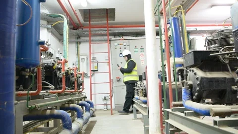 Engineer looking at the high pressure air compressor and writing.	 Vídeo Stock 103868956