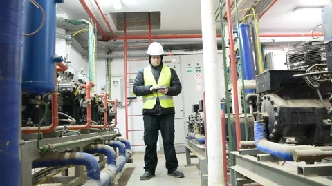 Engineer looking at the high pressure air compressor and writing.	 Vídeo Stock 103870033