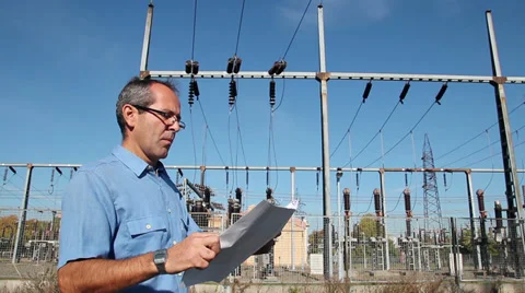 Engineer Looking at Wiring Diagrams Next to Electrical Substation Stock Footage 32771808