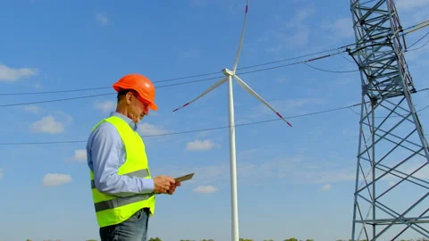 Engineer looks at built windmill station near power lines Stock Footage 164379063