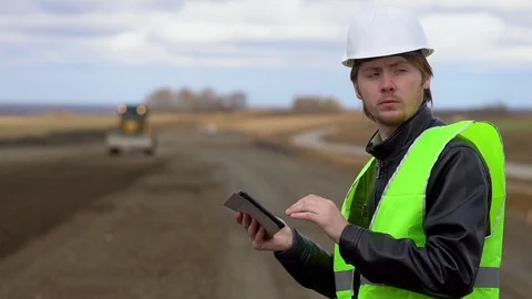 The engineer looks at the construction plan on the tablet and examines the Video stock 100010193
