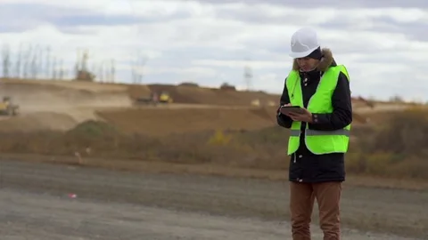 The engineer looks at the construction plan on the tablet, on the background of Video stock 100023795