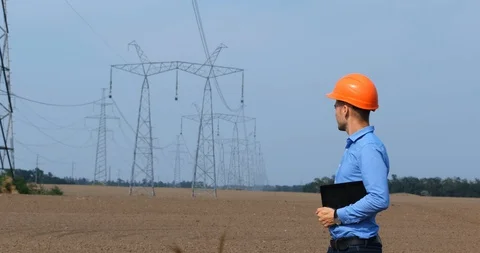 An engineer looks at high-voltage power lines Stock Footage 129469872