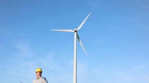 The engineer looks at the windmills and takes notes in the laptop. 動画素材 76564079