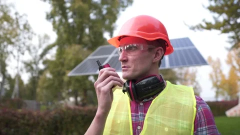 Engineer make call with walkie talkie in solar power plant. Power engineer at Stock Footage 142022981