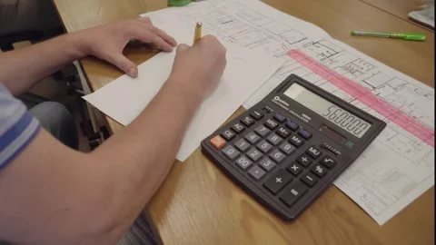 The engineer makes calculations and writes them down on a piece of paper Stock Footage 252033050