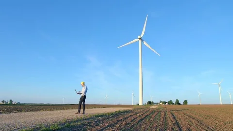 The engineer makes notes in the laptop against the background of windmills. Stock-Footage 76574932