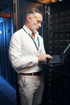 Engineer, man and typing on laptop in server room for maintenance, diagnost.. Foto stock