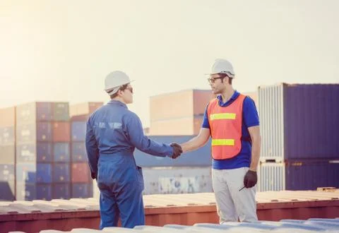 Engineer man handshake on cargo container evening sky blurred background Фото