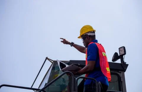 Engineer man in hard hat and safety vest holding laptop standing on container Фото
