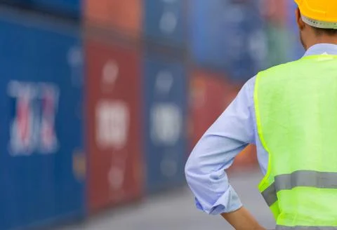 Engineer man in hard hat and safety vest stainding at containers cargo Stockfoto's