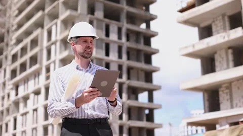 Engineer man in helmet use tablet computer for controls construction of Stock Footage 348559225