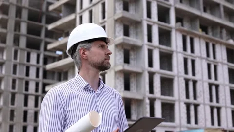 Engineer man in helmet use tablet computer for controls construction of Stock Footage 348559701