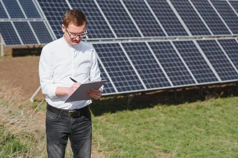 Engineer. Man near solar panel. Worker with a folder. Stock Photos