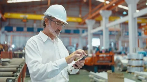 Engineer man typing on smartphone standing in workplace at manufacturing factory 動画素材 237008436