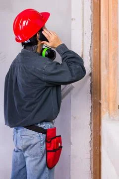 Engineer man wearing hard hat and earmuffs while having a phone call Stock Photos