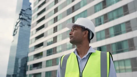 Engineer man in a yellow vest stands in front of a tall building. Stock Footage 280732444