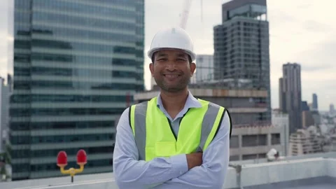 Engineer man in a yellow vest stands on a rooftop in front of a city skylin.. Stock Footage 280732445