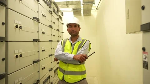 Engineer man in a yellow vest stands in a room full of white cabinets. He i.. Stock Footage 280732466