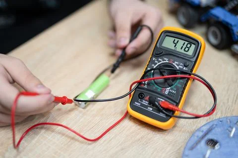 The engineer measures the voltage on the battery with a multimeter Stock Photos