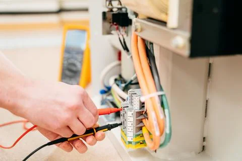The engineer measures the voltage in the electrical appliance. Stock Photos