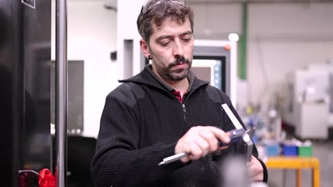 Engineer measuring a piece of metal using a caliper Stock Footage 260013367