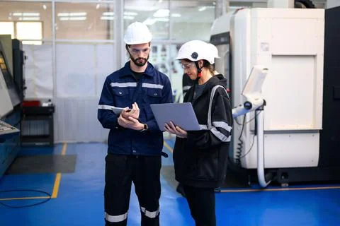 Engineer mechanician operating and controlling CNC machine Stock Photos