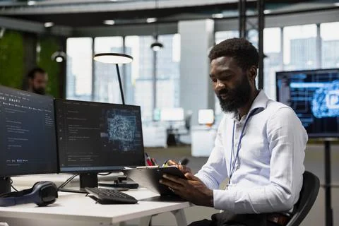Engineer in modern office using AI tools, reading clipboard notes Stockfoto's
