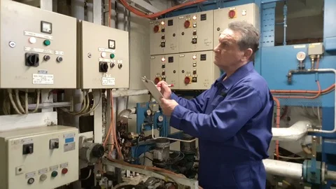 Engineer monitors devices and writes data on paper clipboard 動画素材 116608925