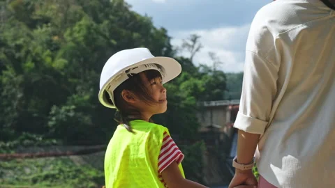 Engineer mother holding her daughter's hand and smiling at each other at dam Stock Footage 229710333