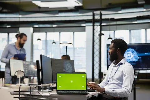 Engineer in office using AI on green screen laptop to streamline app development Stock Photos