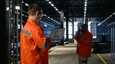 Engineer operates automation software on a laptop to control robot equipment Stock Photos