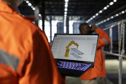 Engineer operates automation software on a laptop to control robot equipment Stock Photos