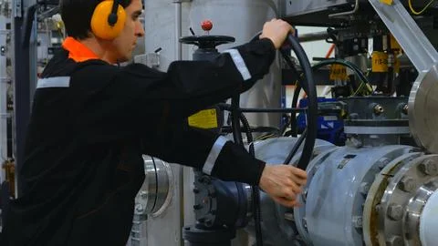 Engineer is operating large valve at industrial facility, demonstrating process Stock Photos