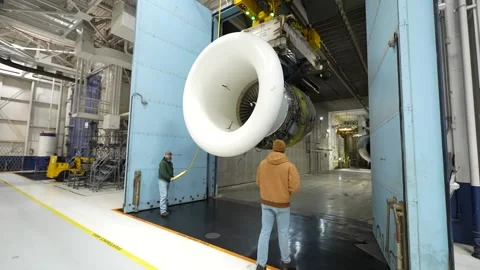 Engineer operating overhead gantry to move aircraft engine at overhaul facility Stock Footage 231690437
