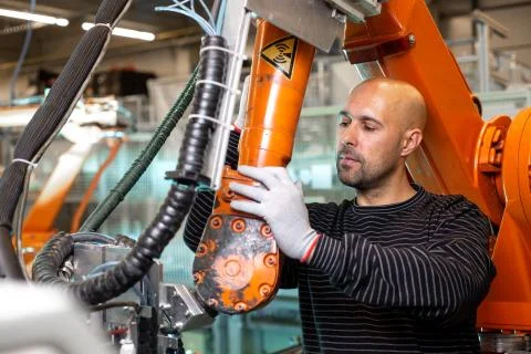 Engineer optimizing production by robotic arm in automotive smart factory Stock Photos