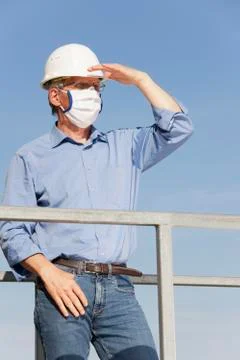Engineer or architect with hard hat and surgical mask because of covid-19 loo Фото