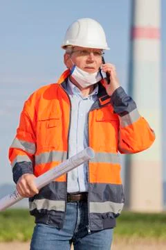 Engineer or architect wearing a face mask beause of coronavirus and blueprint Stock Photos