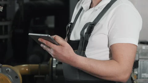 An engineer or factory worker in work uniform uses a digital tablet. Stock Footage 306816577
