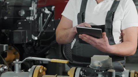 An engineer or factory worker in work uniform uses a digital tablet. Stock Footage 306819580