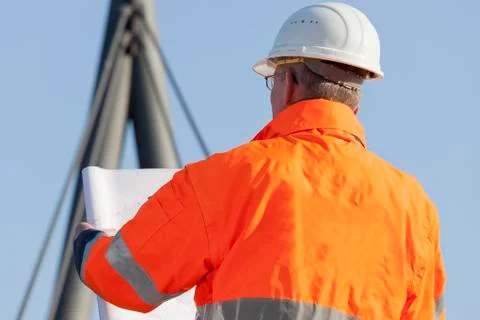 Engineer or foreman with hard hat and protective workwear reading a plan in f Stock Photos