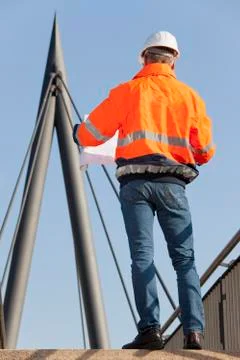 Engineer or foreman with hard hat and protective workwear reading a plan in f Stock Photos