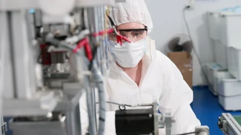 Engineer or technician in protective suite working on medical face mask machine  Stock Footage 158468747
