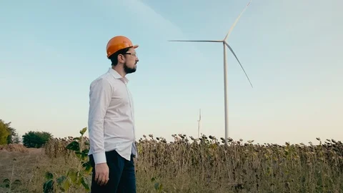 An engineer in an orange protective helmet and goggles looks at an electric Video stock 96517802