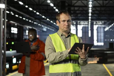 Engineer oversees assembly tools on tablet in industry plant Stock Photos
