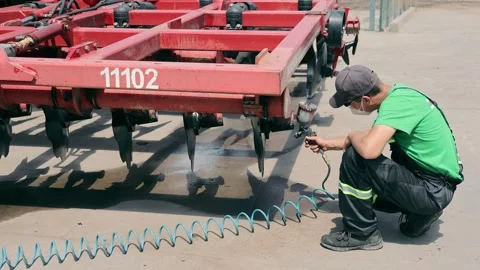 The engineer paints the elements of the housing of agricultural machinery Video stock 252284125